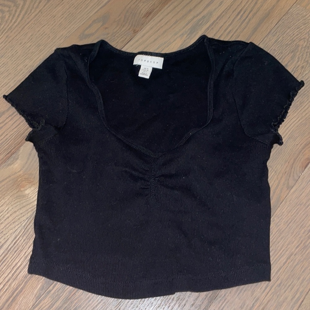 Cropped black T-shirt with a sinched neckline and partly ruffled sleeves.
